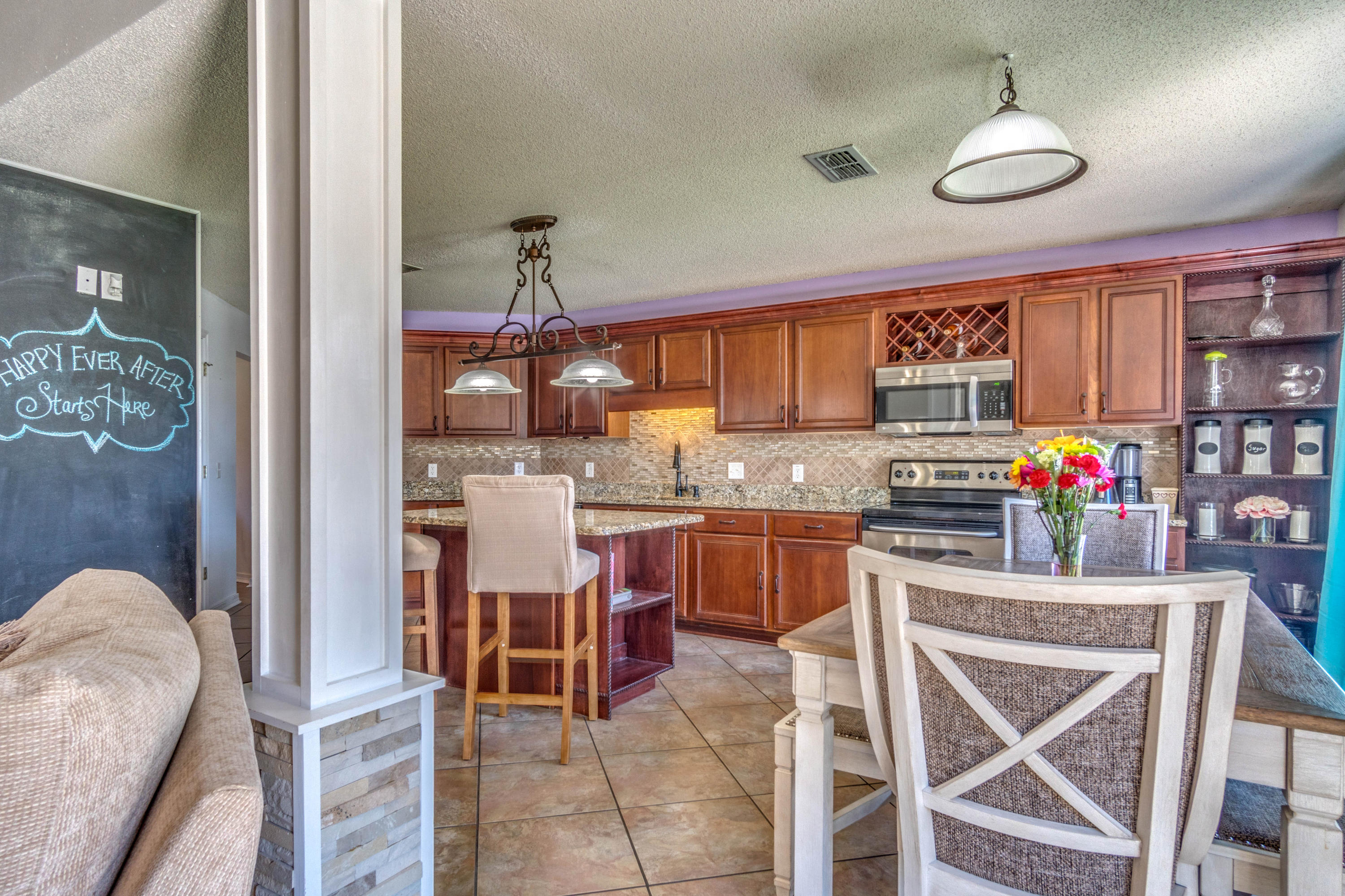 7105 Snug Waters Road Navarre, FL 32566 - Photo 12 of 42 a kitchen with stainless steel appliances granite countertop a stove top oven a sink dishwasher and a dining table with cabinets