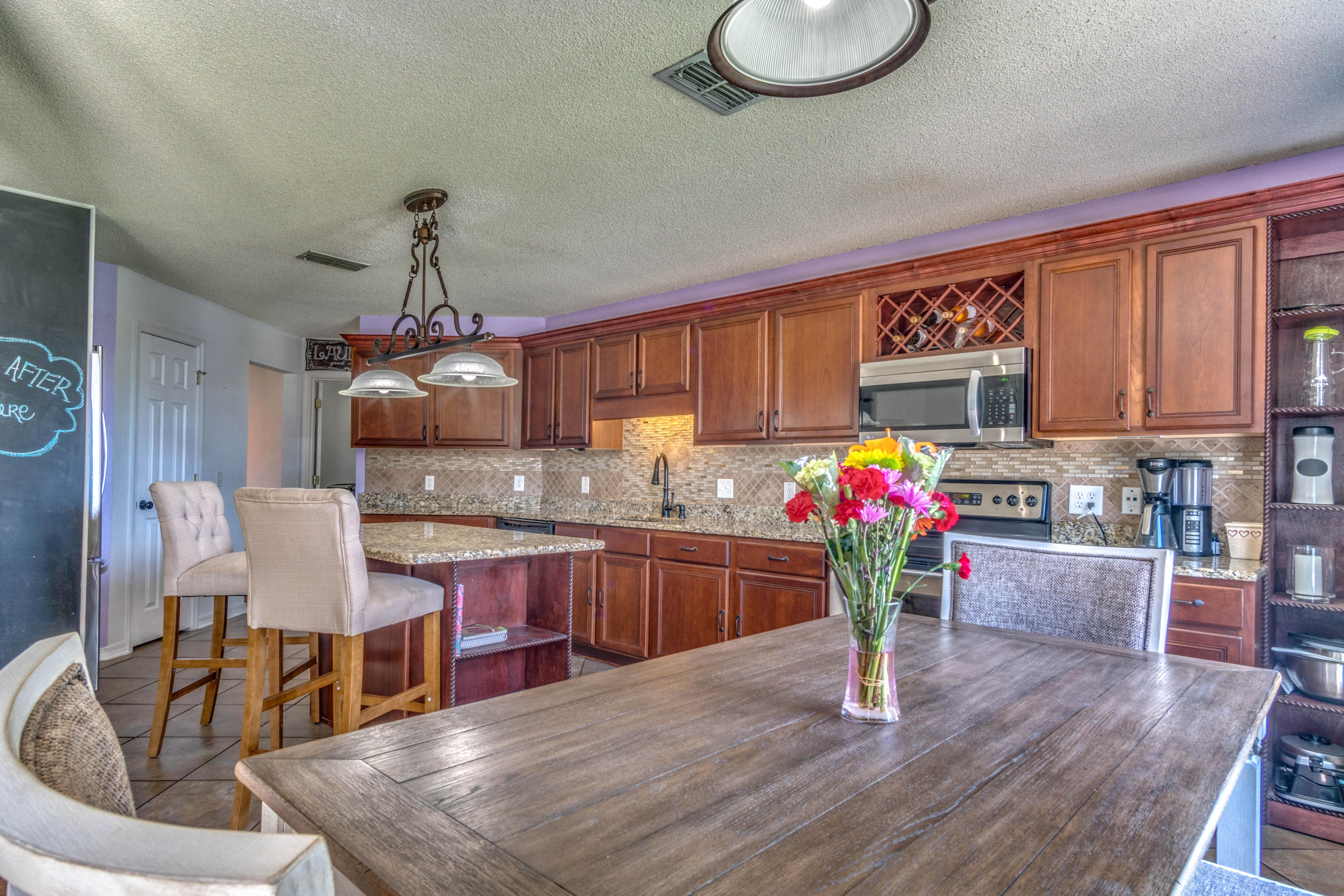 7105 Snug Waters Road Navarre, FL 32566 - Photo 13 of 42 a kitchen with stainless steel appliances granite countertop a kitchen island hardwood floor sink stove dining table and chairs