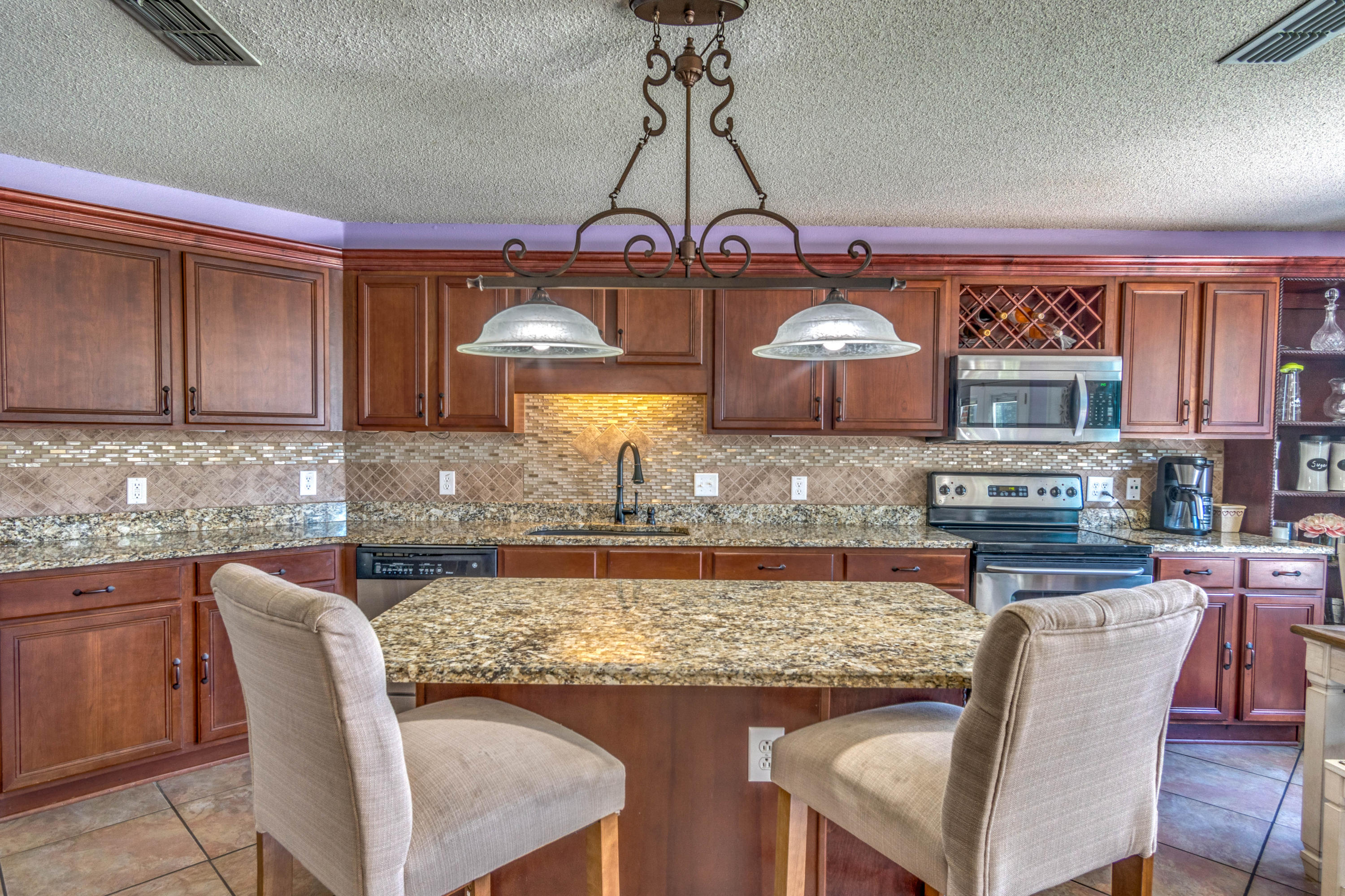 7105 Snug Waters Road Navarre, FL 32566 - Photo 14 of 42 a kitchen with stainless steel appliances granite countertop a stove top oven a dining table and chairs with wooden floor