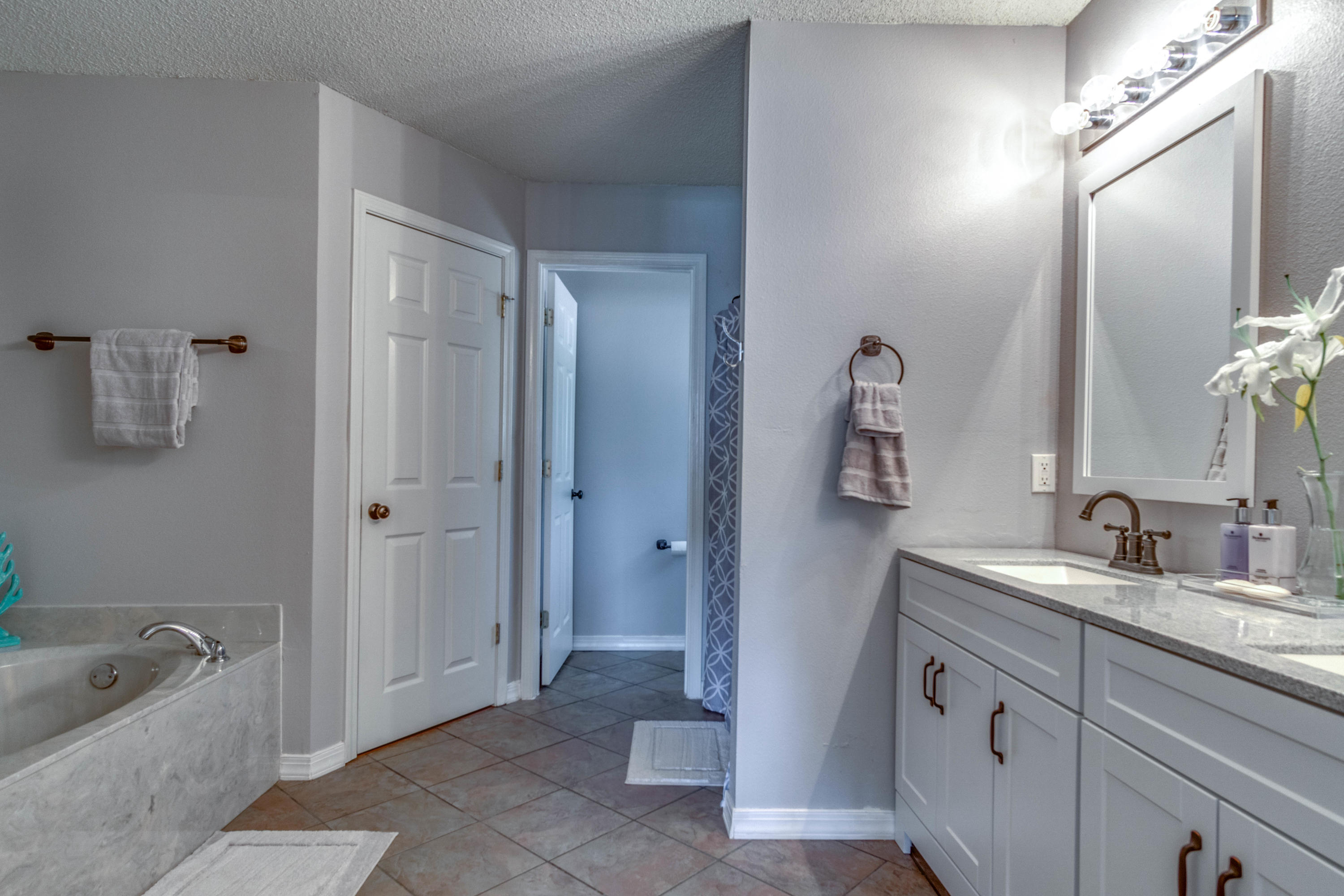 7105 Snug Waters Road Navarre, FL 32566 - Photo 34 of 42 a spacious bathroom with a granite countertop sink mirror and bathtub
