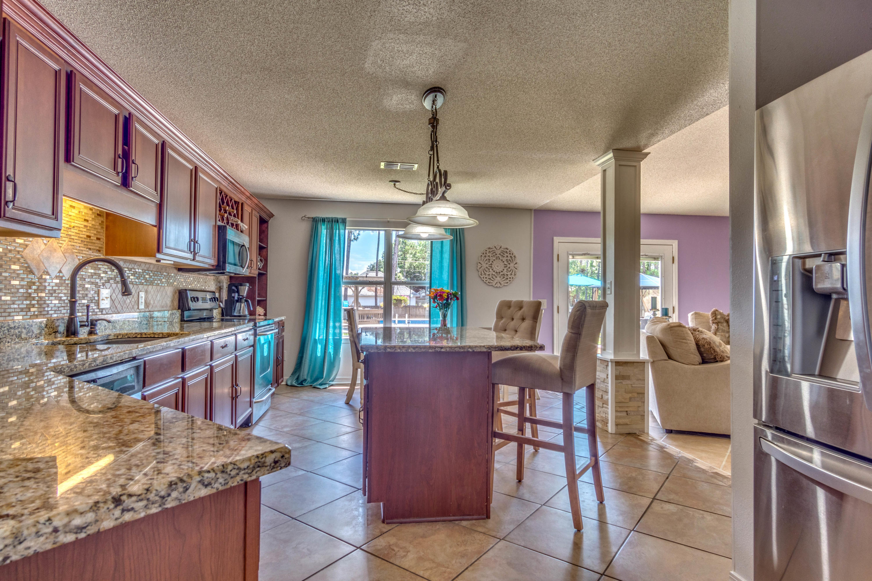 7105 Snug Waters Road Navarre, FL 32566 - Photo 9 of 42 a kitchen with stainless steel appliances granite countertop a refrigerator a oven a sink with island and chairs