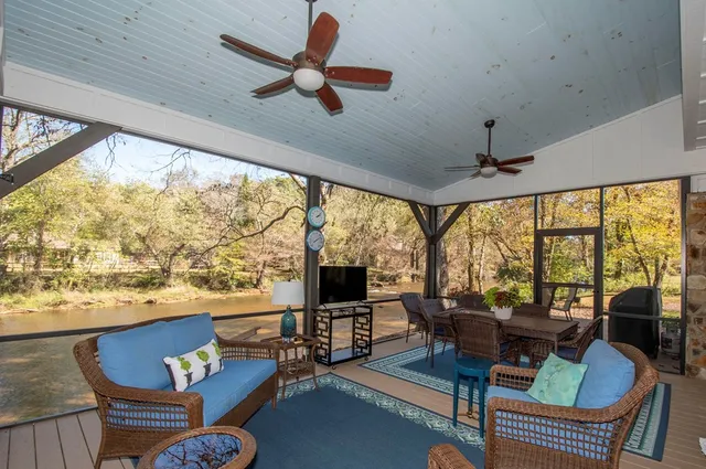 a living room with furniture floor to ceiling windows and a flat screen tv