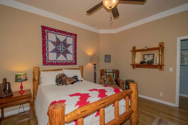 a bedroom with a bed a dresser and wooden floor