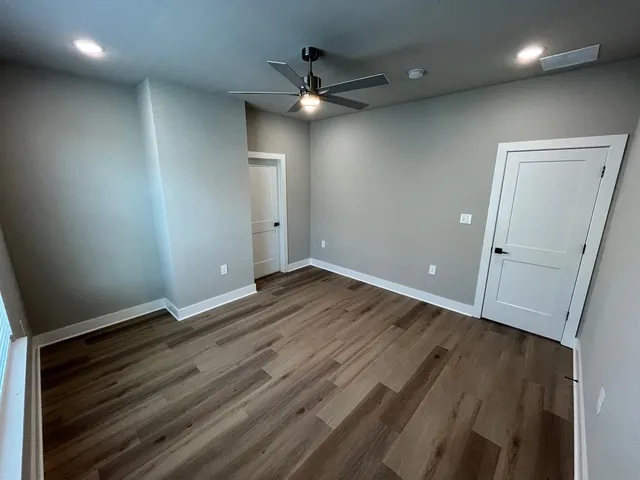 an empty room with wooden floor and a ceiling fan