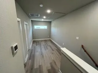 an empty room with wooden floor and fan