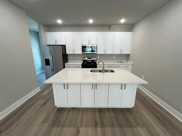 a kitchen with a refrigerator a sink and wooden floor