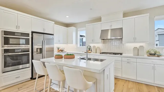 a kitchen with stainless steel appliances a sink a stove a refrigerator and cabinets