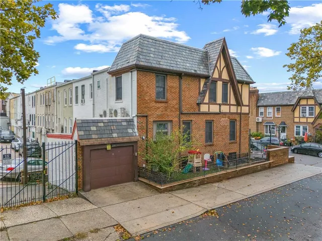 a view of a blue house with a small yard and large trees