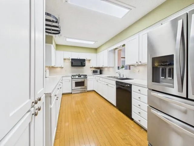 a large white kitchen with a large counter top appliances and cabinets