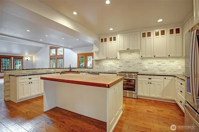 a large kitchen with stainless steel appliances granite countertop a stove and a sink
