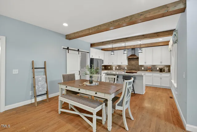 a kitchen with stainless steel appliances granite countertop a refrigerator a stove a sink dishwasher and white cabinets with wooden floor