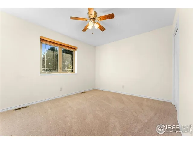 an empty room with a window and a ceiling fan