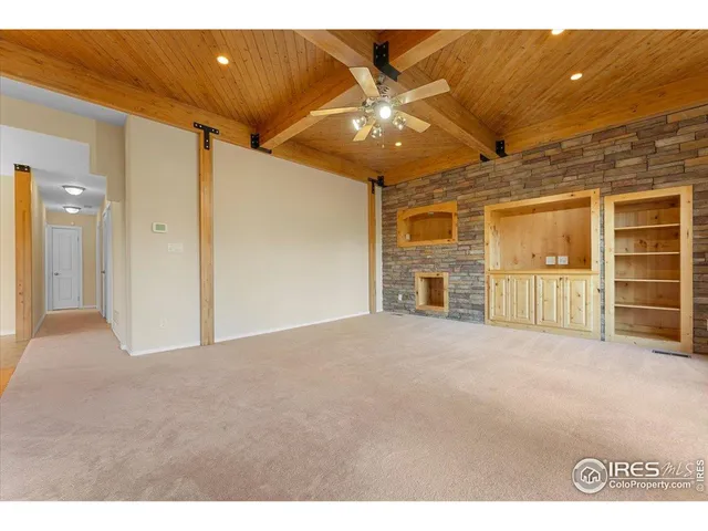 a view of an empty room with a window and kitchen view