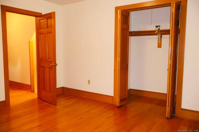 an empty room with an entryway and wooden floor