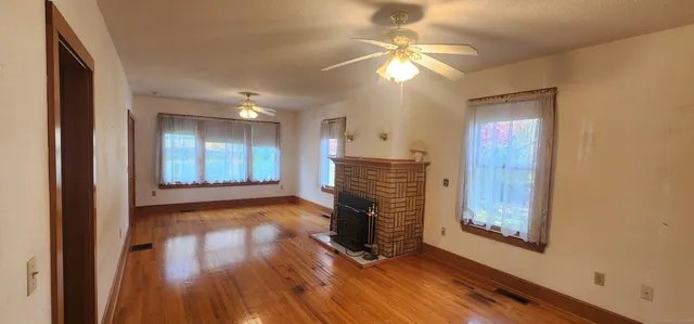 a view of an empty room with wooden floor and a window