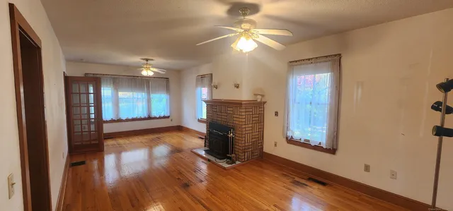 a view of an empty room with window and wooden floor