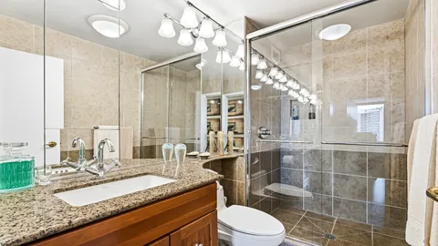 a bathroom with a granite countertop sink a toilet a mirror and shower