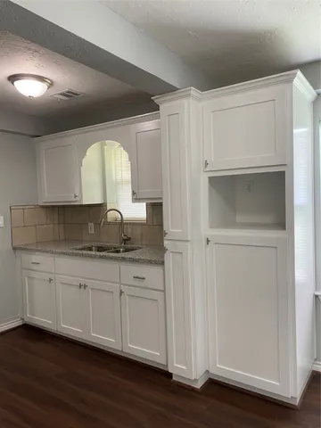 a kitchen with granite countertop white cabinets and a sink