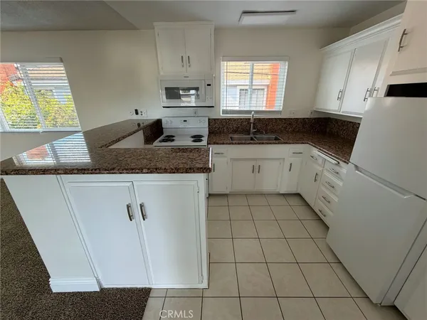 a kitchen with granite countertop white cabinets and white stove