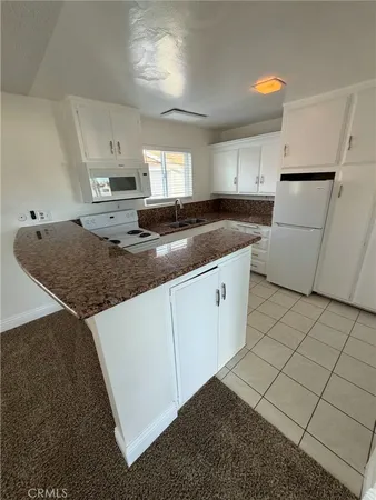 a kitchen with granite countertop a sink stove and cabinets