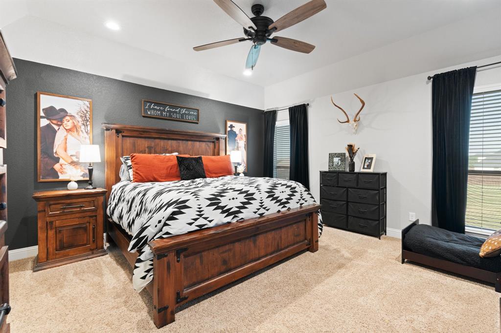 121 Treys Way Godley, TX 76044 - Photo 13 of 32 a bedroom with a large bed and a chandelier