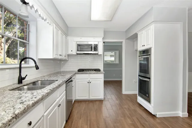 a kitchen with a sink wooden floor and stainless steel appliances