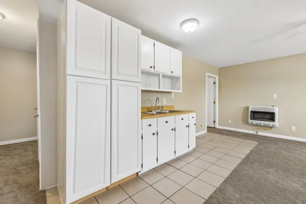 a kitchen with granite countertop a stove a sink and a refrigerator with white cabinets