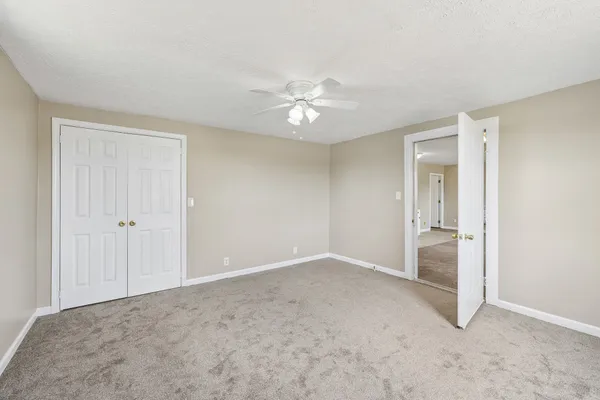 a view of an empty room and chandelier fan