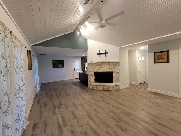 an empty room with wooden floor fireplace and windows