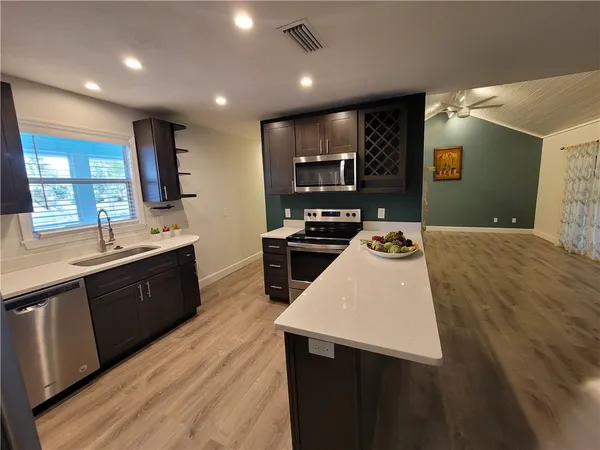 a large kitchen with kitchen island a sink wooden floor and black appliances