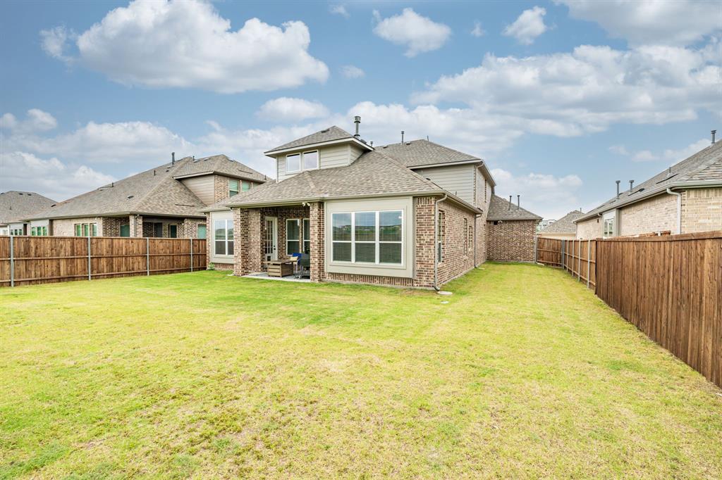 313 Tate Lane Anna, TX 75409 - Photo 28 of 30 Expansive rear yard featuring a manicured lawn, full privacy fencing, and a covered patio area