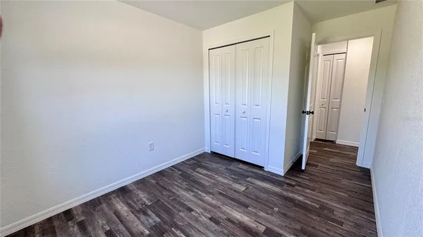 a view of an empty room with wooden floor and closet