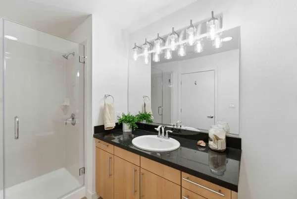 a bathroom with a granite countertop sink a mirror and a shower