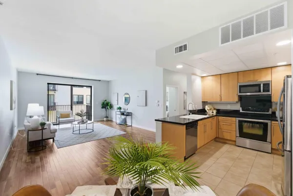a living room with stainless steel appliances granite countertop furniture a couch and a view of kitchen