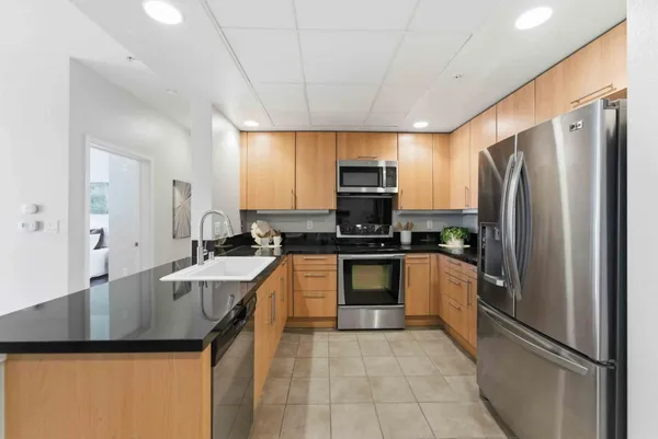 a kitchen with stainless steel appliances granite countertop a sink a stove a refrigerator a washer dryer and white cabinets