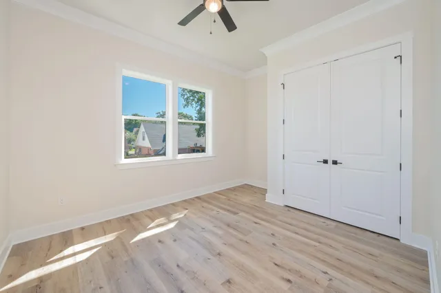 an empty room with wooden floor and ceiling fan