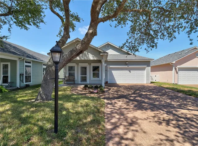 a view of a yard in front of a house with a large tree