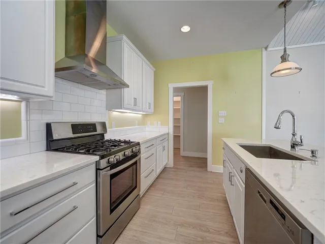 a kitchen with stainless steel appliances granite countertop a sink a stove top oven a counter space and cabinets