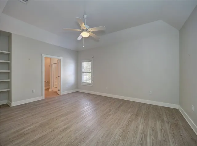 a view of an empty room with wooden floor and window