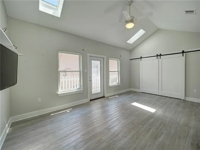 a view of an empty room with wooden floor and a window