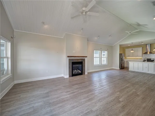 an empty room with wooden floor fireplace and windows