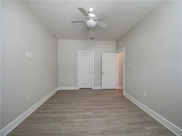 a view of an empty room with a ceiling fan and wooden floor