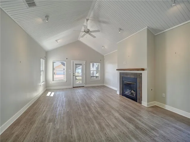 an empty room with wooden floor fireplace and windows