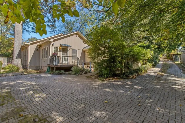 a view of a house with a small yard and large trees