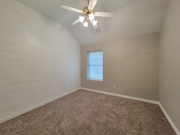 an empty room with a window and a fan