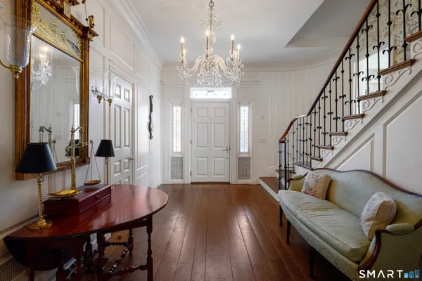 a view of a dining room and livingroom with furniture wooden floor a rug and a chandelier