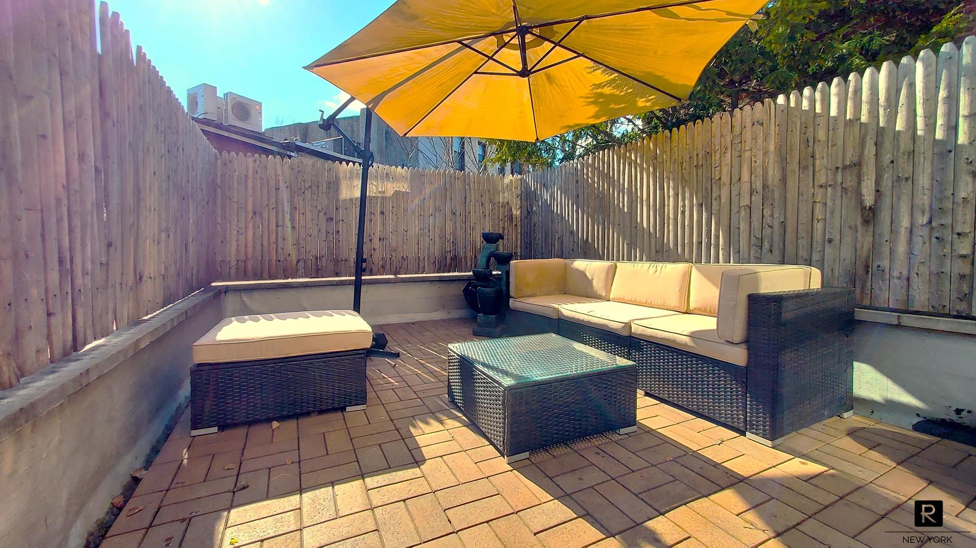 a backyard of a house with couches and umbrella