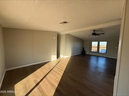 a view of empty room with wooden floor and fan