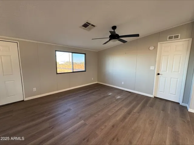 an empty room with wooden floor ceiling fan and windows