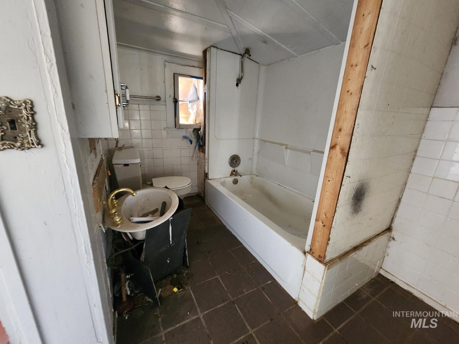 708 15th Avenue Lewiston, ID 83501 - Photo 7 of 12 Bathroom with tile walls, dark tile patterned floors, and bathing tub / shower combination